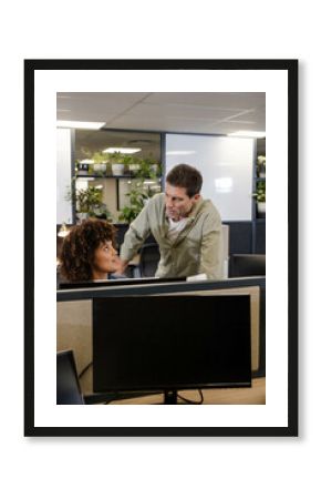 Discussing Diverse coworkers exchanging ideas at cubicle desks in open-plan office, with monitors