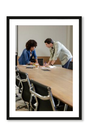 Leaning Diverse coworkers reviewing documents and writing at table in office, with coffee
