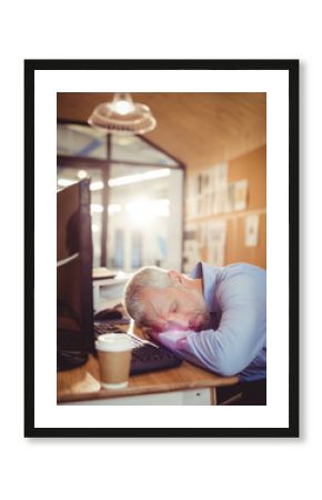 Office worker sleeping at desk with monitor keyboard mouse and coffee cup in glass-walled office