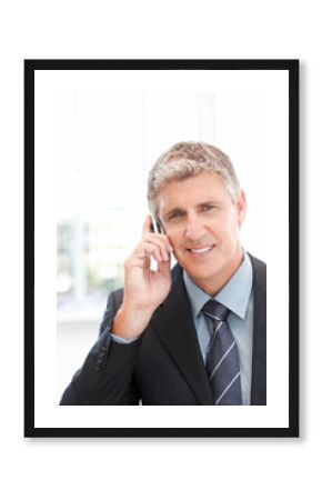 Businessman talking on smartphone while standing in office wearing dark suit and striped tie