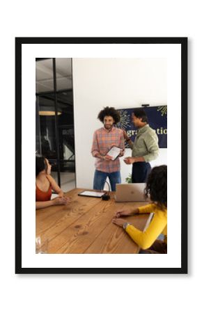 Diverse business team discussing project with tablet and laptop in modern office