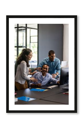 Collaborating around computer, team working together in modern office environment
