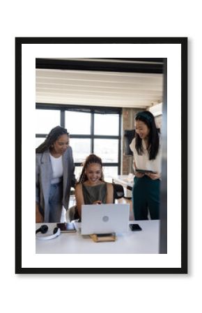 Diverse business team celebrating success while looking at laptop in modern office