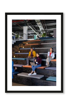 Diverse coworkers participating in team workshop using microphone, laptop, tablet in office lounge