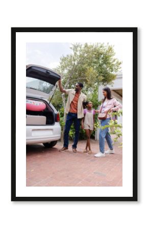 Family packing car with luggage and pool float, excited for vacation trip