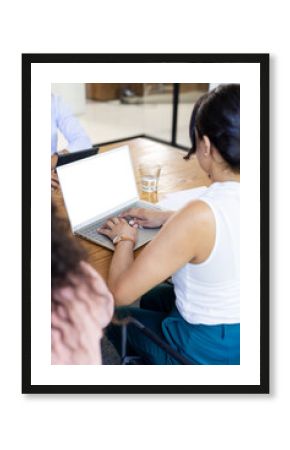 Typing on laptop, woman collaborating with diverse colleagues during office meeting, copy space