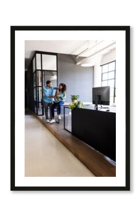 Diverse colleagues discussing project while using tablet in modern office space, copy space