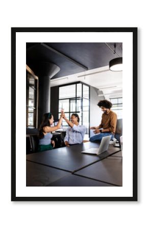 Team celebrating success in modern office with high-fives and laughter, copy space