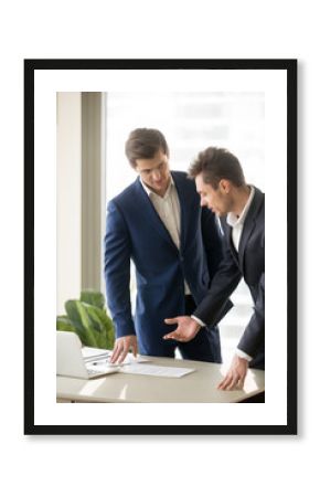 Two appraisers working on architectural project with laptop and building plan, partners considering construction investment, buying commercial property, discussing structured design, vertical view