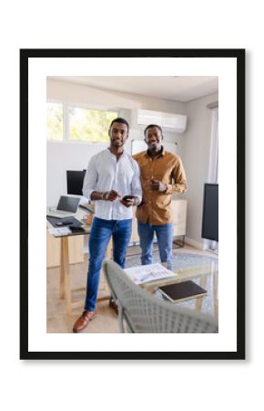 Two friends standing in modern office holding smartphones, smiling confidently