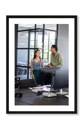 Colleagues discussing project in modern office, standing near large windows