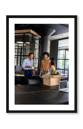 Colleagues in modern office unpacking box, smiling and enjoying conversation