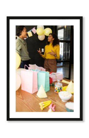Colleagues discussing at office party with gift bags and decorations on table