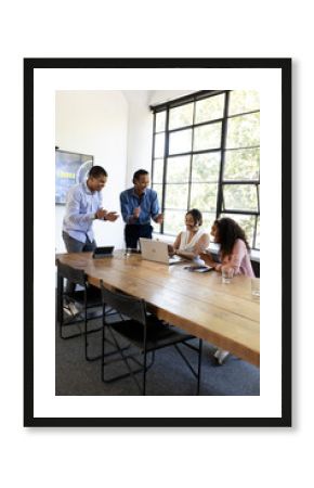 In office, diverse team collaborating on laptop, enthusiastically sharing ideas