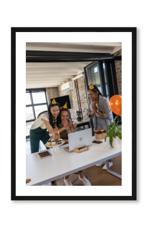 Colleagues celebrating birthday with cupcakes and video call in modern office