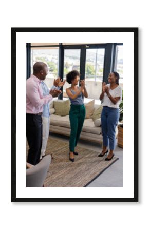 Colleagues applauding and celebrating success in modern office with large windows