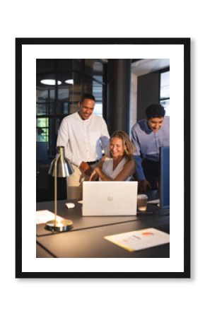 Colleagues collaborating on laptop in modern office, smiling and discussing project