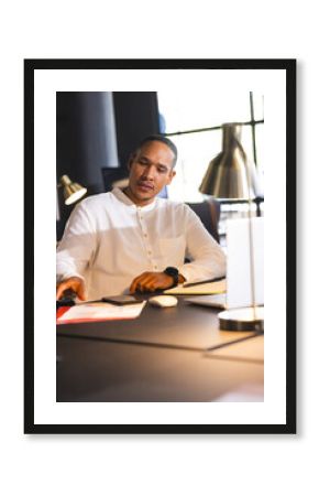 Businessman in white shirt working late at desk with documents and laptop