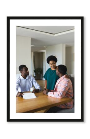 Reviewing documents African American colleagues at conference table in office, with papers and mug