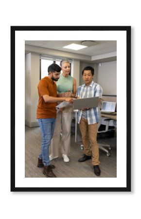 Collaborating Diverse coworkers analyzing data in open-plan office, with laptop and paper printouts