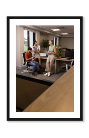Diverse coworkers collaborating around workstation in modern office, with printed documents