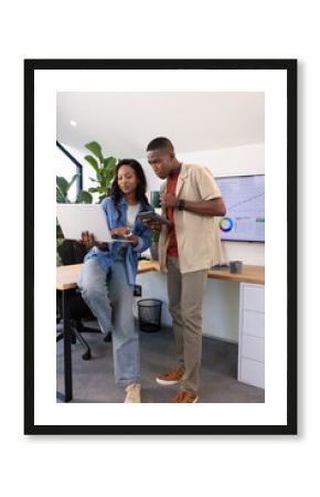 African American colleagues collaborating in office on laptop, with smartphone and coffee mug