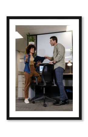 Diverse coworkers discussing data trends at office desk, with tablet and bar chart monitor