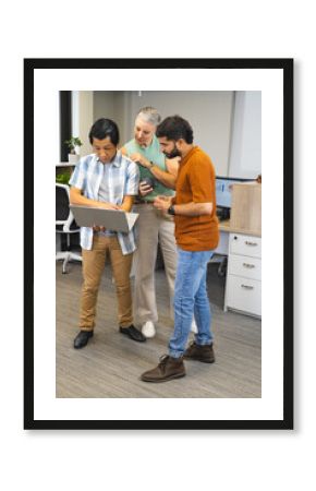 Brainstorming diverse coworkers reviewing project around laptop in office, with coffee mug