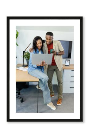 Collaborating African American colleagues examining charts at office, holding laptop and green mug