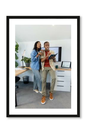 Leaning African American team collaborating at office desk, holding mug and notebook, copy space