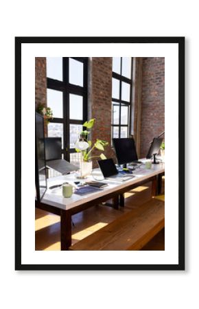 Modern office workspace with multiple laptops and monitors on wooden table, copy space