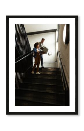 Examining open binder diverse coworkers standing on stairwell landing, with skylight, copy space