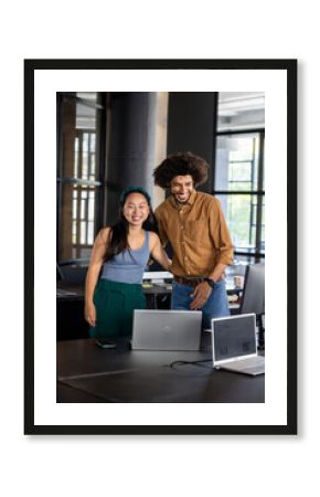 Colleagues in modern office smiling and collaborating on laptop project