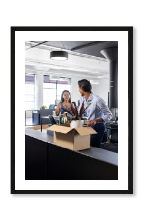 Colleagues in modern office unpacking boxes and discussing new workspace setup
