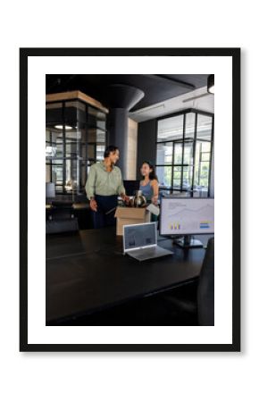 Colleagues discussing project while unpacking box in modern office workspace