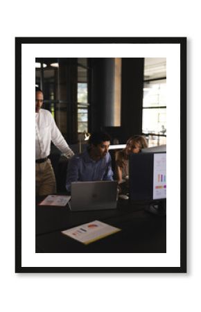 Collaborating on project, business professionals using laptop and charts in office