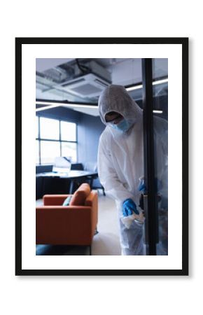 Person in protective suit cleaning office door handle, ensuring workplace safety, copy space