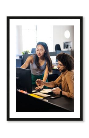 Diverse colleagues collaborating at office, discussing project details on computer screen
