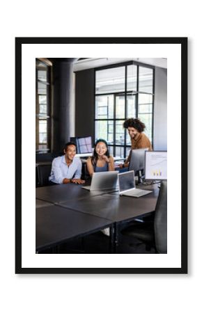 Diverse team collaborating on laptops in modern office, discussing digital analytics
