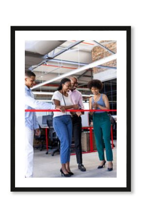 Diverse colleagues celebrating office opening, cutting red ribbon with joyful expressions