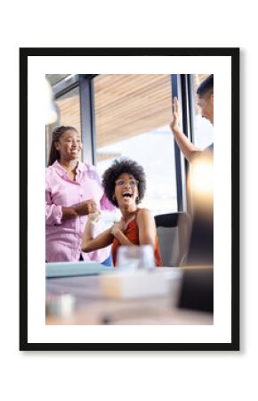 diverse colleagues celebrating success in office, smiling and high-fiving