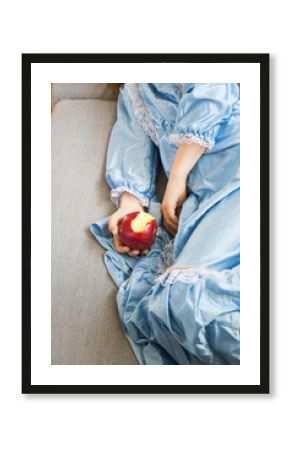 Little girl dressed up as a princess holding bitten red apple, partial view