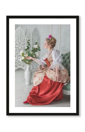 Beautiful woman in old-fashioned medieval dress on the sofa