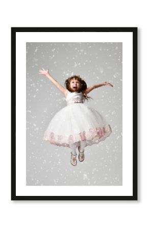 girl jumping in the white communion winter dress under heavy snow with arms spread screaming yelling