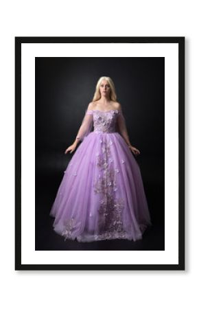 full length portrait of a blonde girl wearing a fantasy fairy inspired costume,  long purple ball gown with fairy wings,   standing pose  on a dark studio background.