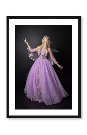  full length portrait of a blonde girl wearing a fantasy fairy inspired costume,  long purple ball gown with fairy wings,   standing pose  on a dark studio background.