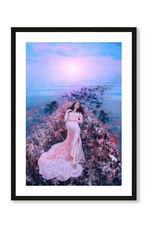 Fairy princess sleeping beauty in magical boat decorated with white red flowers tree branches. Trail of leaves water. long flowing hair brunette. pink long dress. Backdrop bright sky sunset sea waves