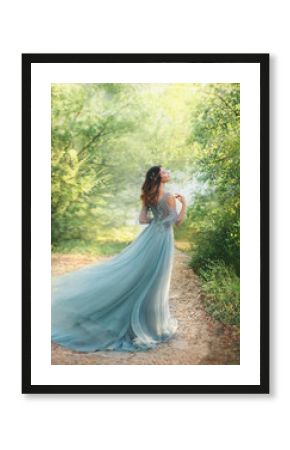 fairy tale princess in light summer blue, turquoise dress standing in park. Happy Woman walks towards wind, graceful dancing girl goddess in image of flower. flying long hem of dress. nymph of forest