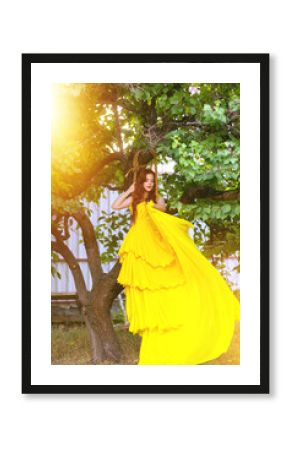 A fragile, tender girl in a yellow vintage dress on a tree. Artistic Photography