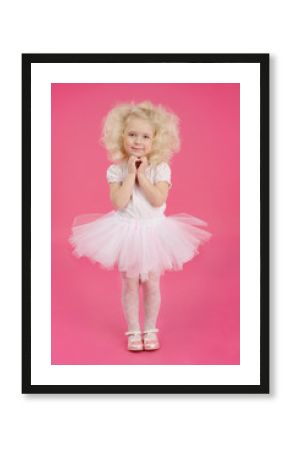 Little girl in a tutu skirt on pink background